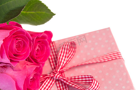 粉红玫瑰靠在粉红色圆点包裹的礼物上
