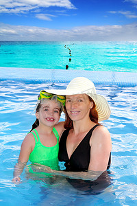 母亲和女儿在热带海滩泳池拥抱