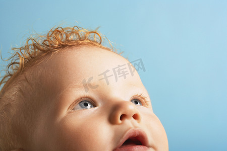 大头贴可爱相框摄影照片_孤立在蓝色背景上的可爱男婴的特写