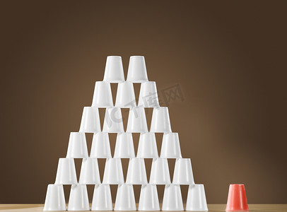 多面体几何摄影照片_桌上的白色塑料杯金字塔紧挨着单个红色杯子