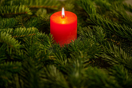 红色大气背景摄影照片_诺德曼冷杉树枝环绕着红色燃烧蜡烛的圣诞主题