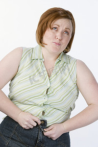 肥胖女性无法扣上与白色背景隔离的牛仔裤