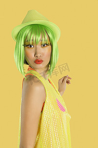 黄色背景下，一头绿色头发、嘴唇皱起的时髦年轻女子的画像