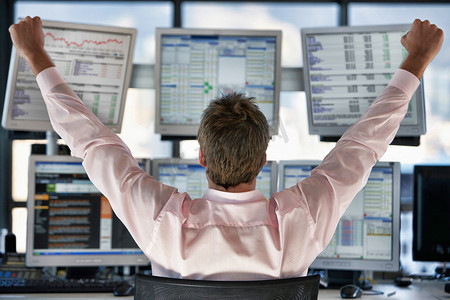 股票交易员在电脑屏幕上庆祝的后视图