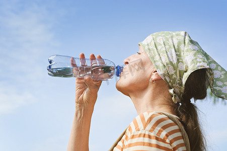 女性喝水摄影照片_高级女人从瓶子里喝水