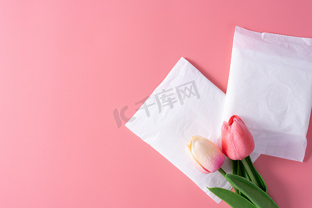 郁金香花摄影照片_卫生巾，粉红色背景上带郁金香花的卫生巾。