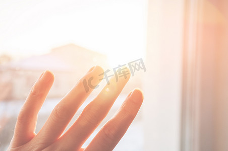 阳光下的背景摄影照片_在金色阳光下，手指伸开的女手