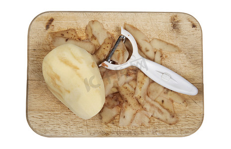 在木砧板上剥皮的生土豆，削皮器被切掉