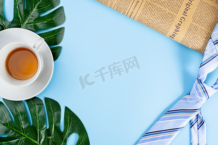 父亲节快乐背景概念，蓝色领带、报纸、叶子和蓝色背景的茶杯，带有文本复制空间。