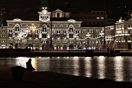 夜间钓鱼摄影照片_夜间在城市钓鱼的人