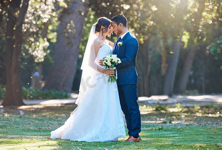 一对年轻的混血夫妇站在草地上庆祝他们的婚礼的全长镜头。