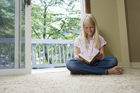 女孩（7-9岁）盘腿坐着看书微笑