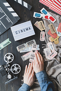 爆米花电影票摄影照片_女性手持复古电影票、带 Cinema 字样的灯箱、拍板和 3D 眼镜的顶视图