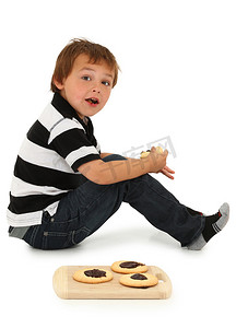 可爱的六岁白人男孩坐在地板上吃糖