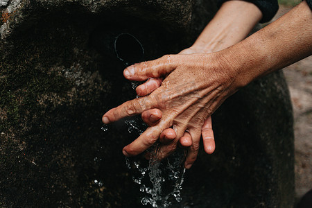 海的字体摄影照片_老妇人在乡村字体中用结冰的水洗手的特写