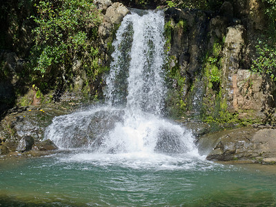 瀑布从岩石上倾泻而下，汇入平静的水池