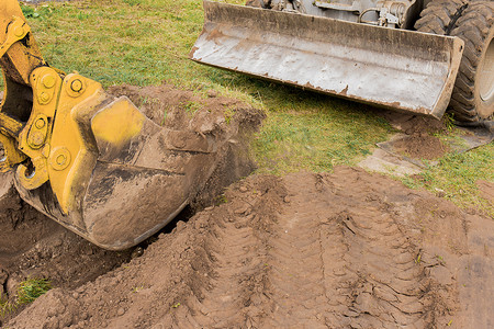 一堆泥土摄影照片_一桶挖掘机用一堆泥土在建筑工地上挖了一个洞。