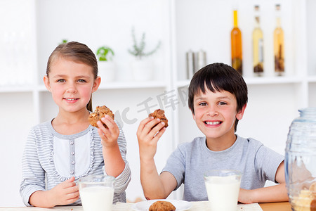 吃饼干和喝牛奶的微笑的兄弟姐妹