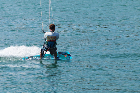 海里冲浪摄影照片_一个男人在阳光明媚的日子里在海里放风筝