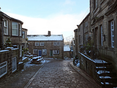 雪街道摄影照片_冬天，历史悠久的约克郡 heptonstall 村，屋顶和街道都被雪覆盖