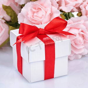 粉红色的花朵和礼盒，上面有红丝带和白色 ba 上的蝴蝶结