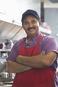 西班牙裔拉丁自信男子双臂交叉站在餐厅厨房里的肖像
