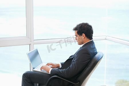 坐在椅子上的人摄影照片_在电脑上打字时坐在椅子上的人