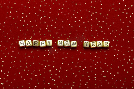 带有亮片的红色天鹅绒上珠子的短语“新年快乐”