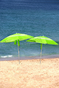 沙滩上的两把绿色太阳伞