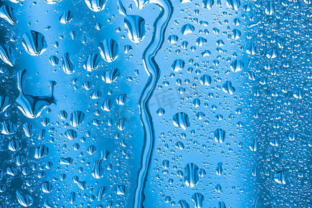 水面气泡摄影照片_带水滴的抽象背景装饰品。雨天玻璃上的雨滴。玻璃上闪闪发光的水面。水滴呈球状或球状。蓝色雨滴