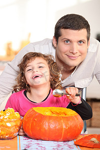 一位父亲和他的小女儿笑着吃南瓜