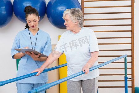 老年妇女与治疗师一起用双杠走路