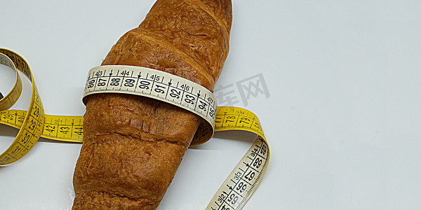 羊角面包上包裹着柔软的测量尺，作为不健康营养的象征