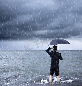 暴雨摄影照片_暴雨背景下拿着雨伞的心烦意乱的商人