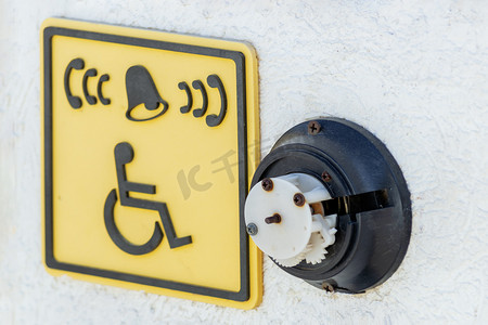 一个坏掉的残疾人呼叫按钮和通往海滩的楼梯前的标志图标。