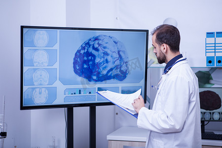 上脑摄影照片_医生在他的剪贴板上检查病人的大脑分析