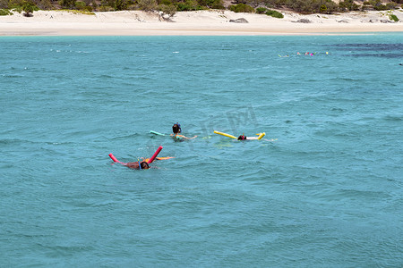 人们在沙岛附近的浅珊瑚礁上浮潜