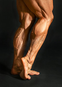健美运动员摄影照片_黑色 backgr 上男性健美运动员后腿小腿肌肉的细节