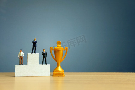 微型商业概念 — 商人站在白人领奖台前，拿着金奖杯