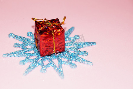 粉红色背景中的蓝色雪花和红色礼盒，圣诞背景的复制空间