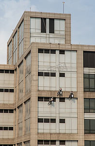 一群工人在高层办公楼清洁窗户服务。