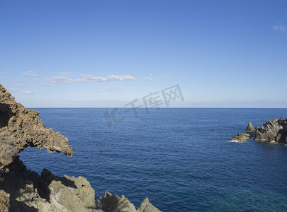 前方有尖锐岩石和悬崖的海平面，真实的蓝天背景