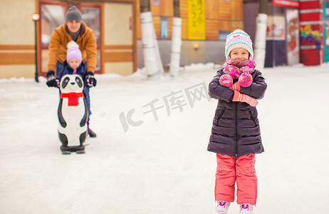 溜冰场上可爱的小女孩，背景是爸爸和可爱的妹妹
