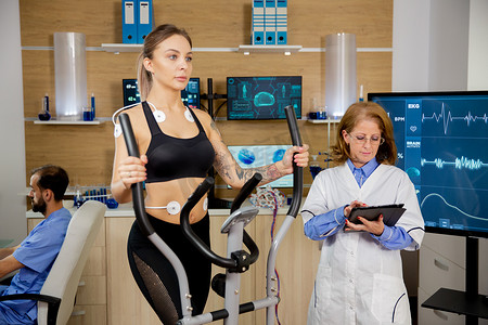 在踏步机上进行测试的女运动员和医生跟随她的平板电脑进化
