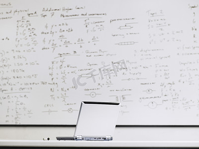 教室桌上的笔记本电脑，背景是白板