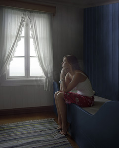 一个年轻体贴而悲伤的女人独自坐在房间里的侧视图