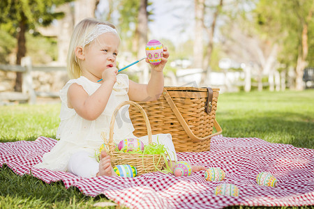 野餐毯摄影照片_可爱的小女孩在野餐毯上给复活节彩蛋上色