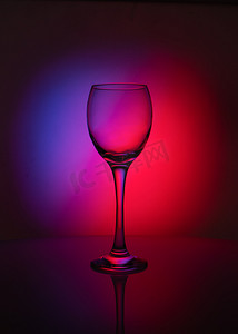 紫色酒杯摄影照片_红色和紫色背景上透明玻璃的轮廓