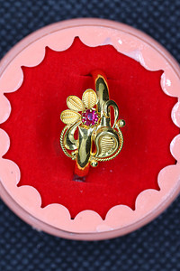 一枚红色钻石金戒指，为女孩设计了花朵图案和精美的图画