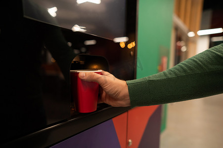 白人男子从自动售货机给自己倒咖啡。